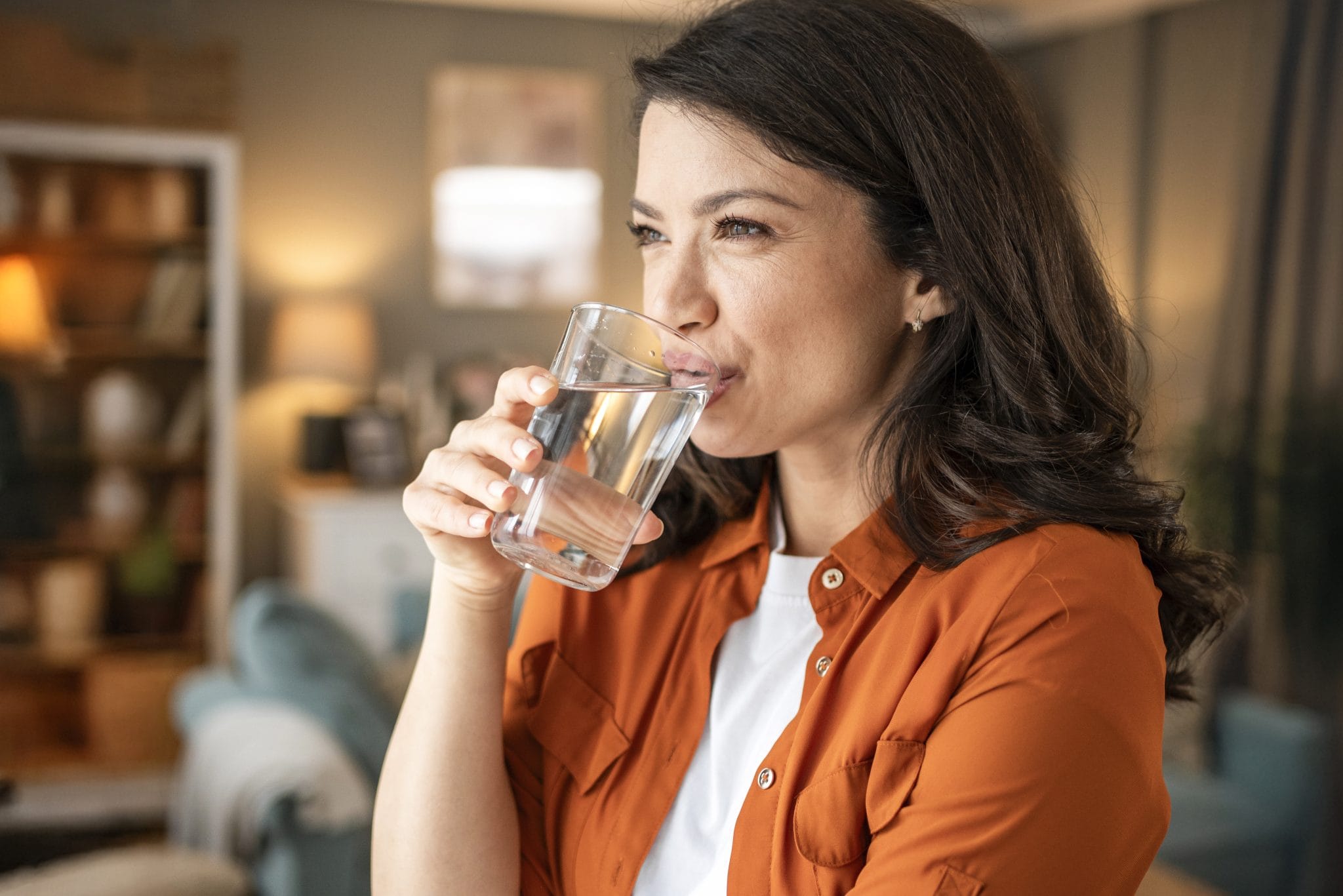 A boy and a girl drink water from a glass in nature on a sunny day